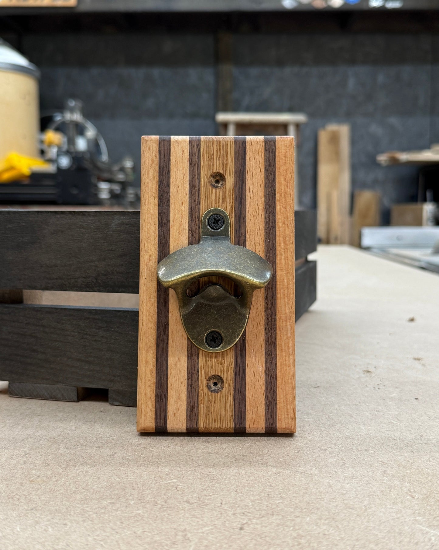 Wooden bottle opener with metal cap catcher on a concrete floor.