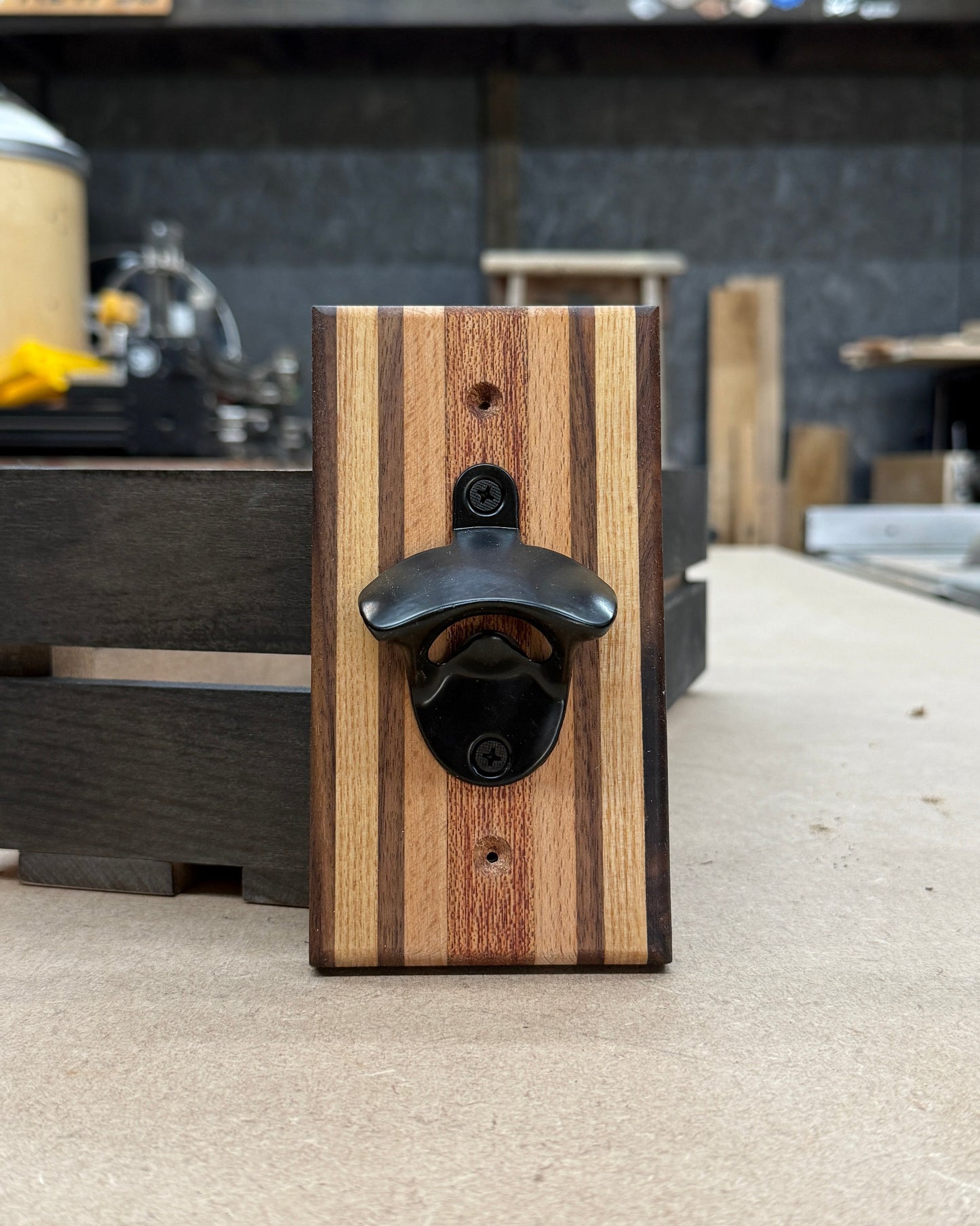 Wooden bottle opener with black cap on a concrete surface, blurred background