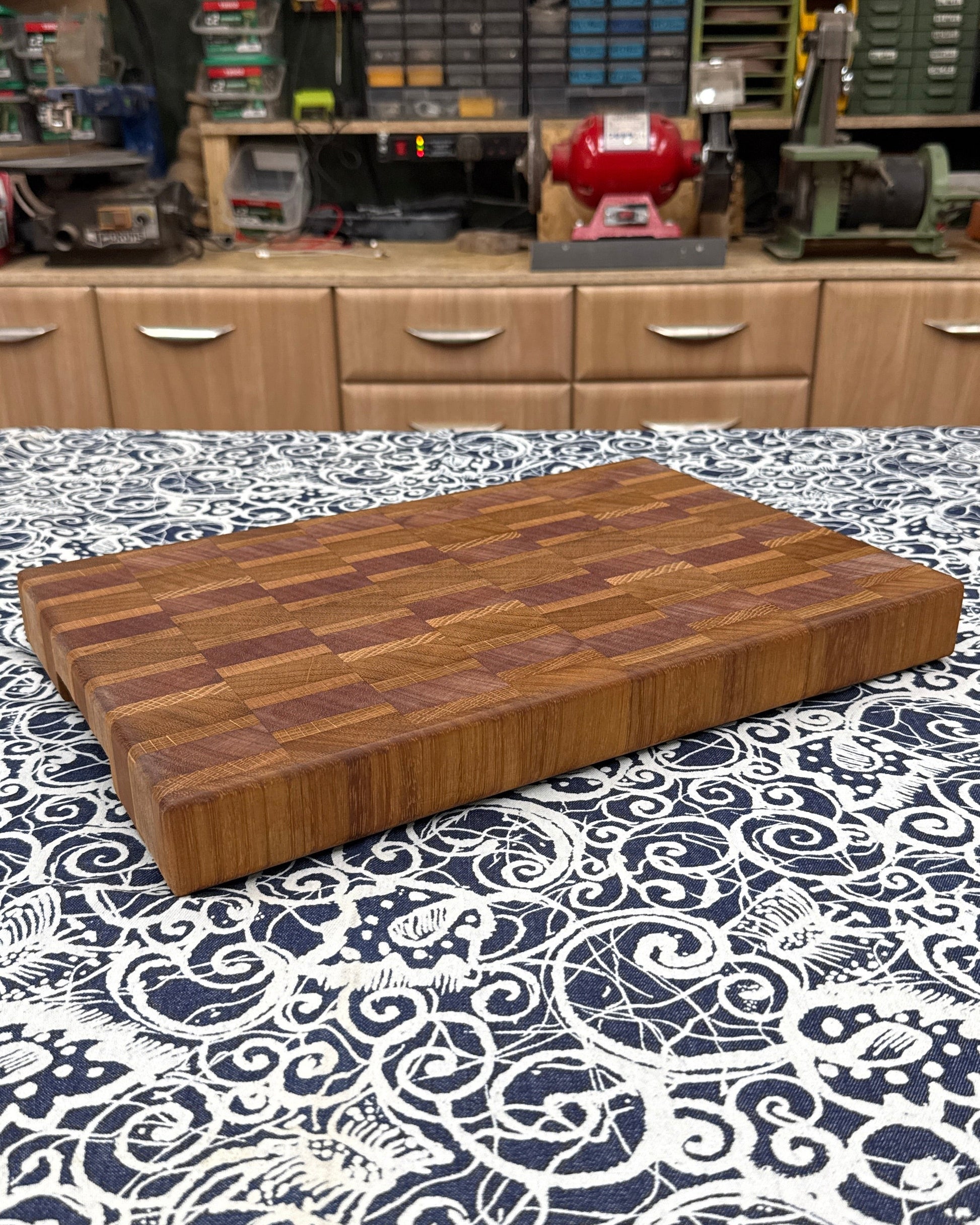 Wooden cutting board on a patterned surface with a workshop in the background