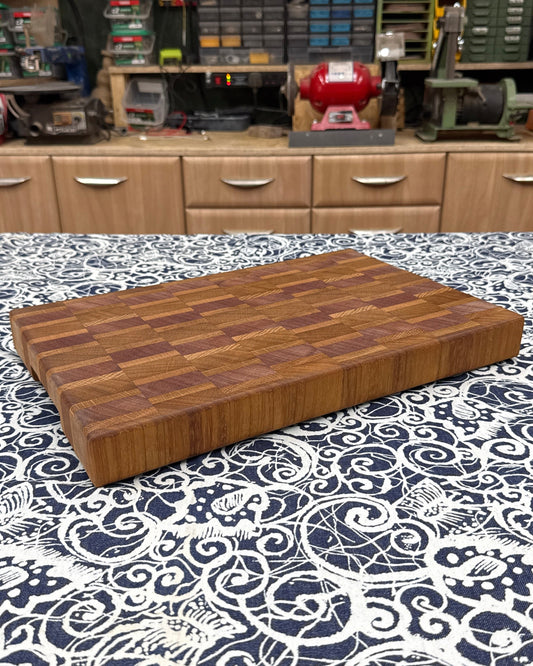 Wooden cutting board on a patterned surface with a workshop in the background