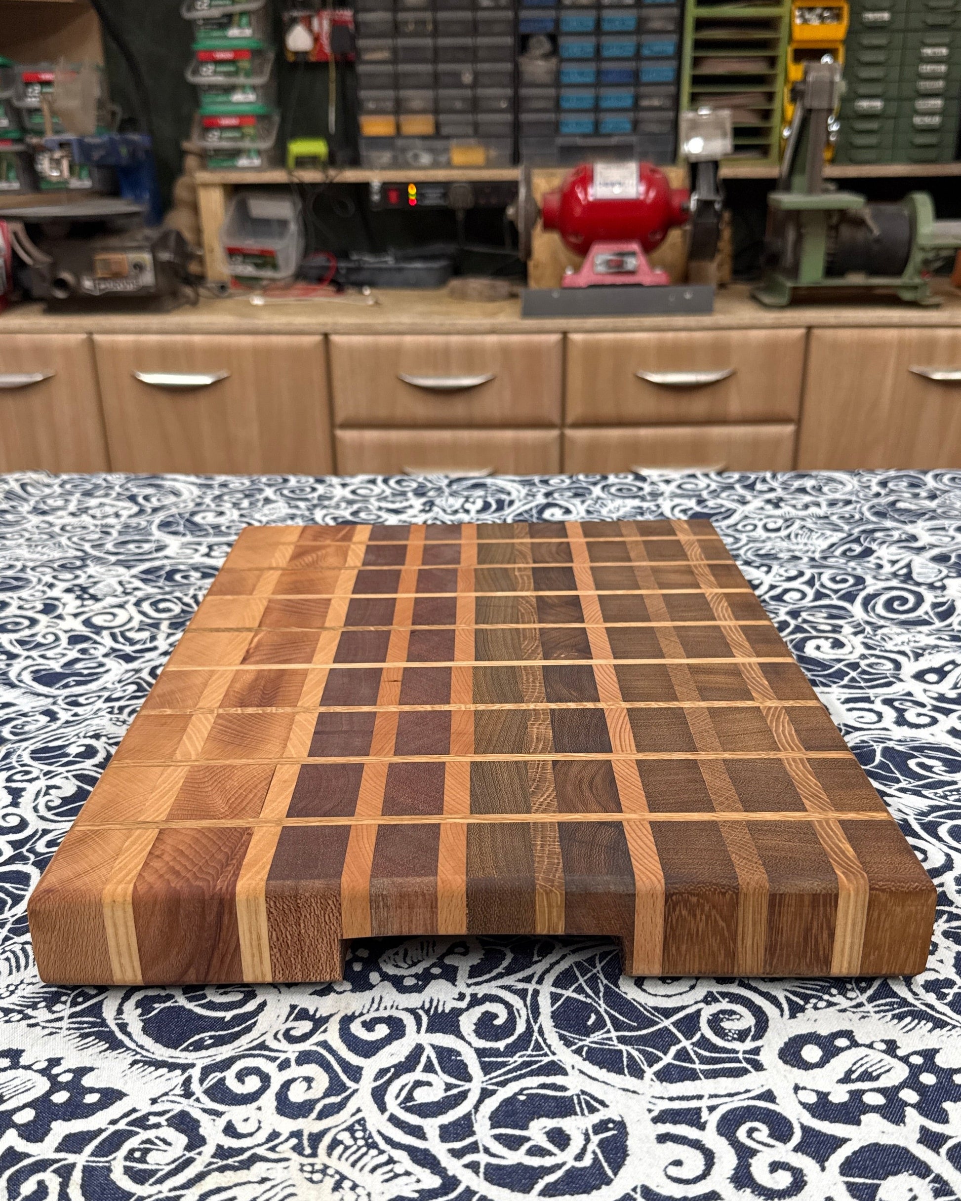 Wooden cutting board on a patterned surface with a workshop in the background