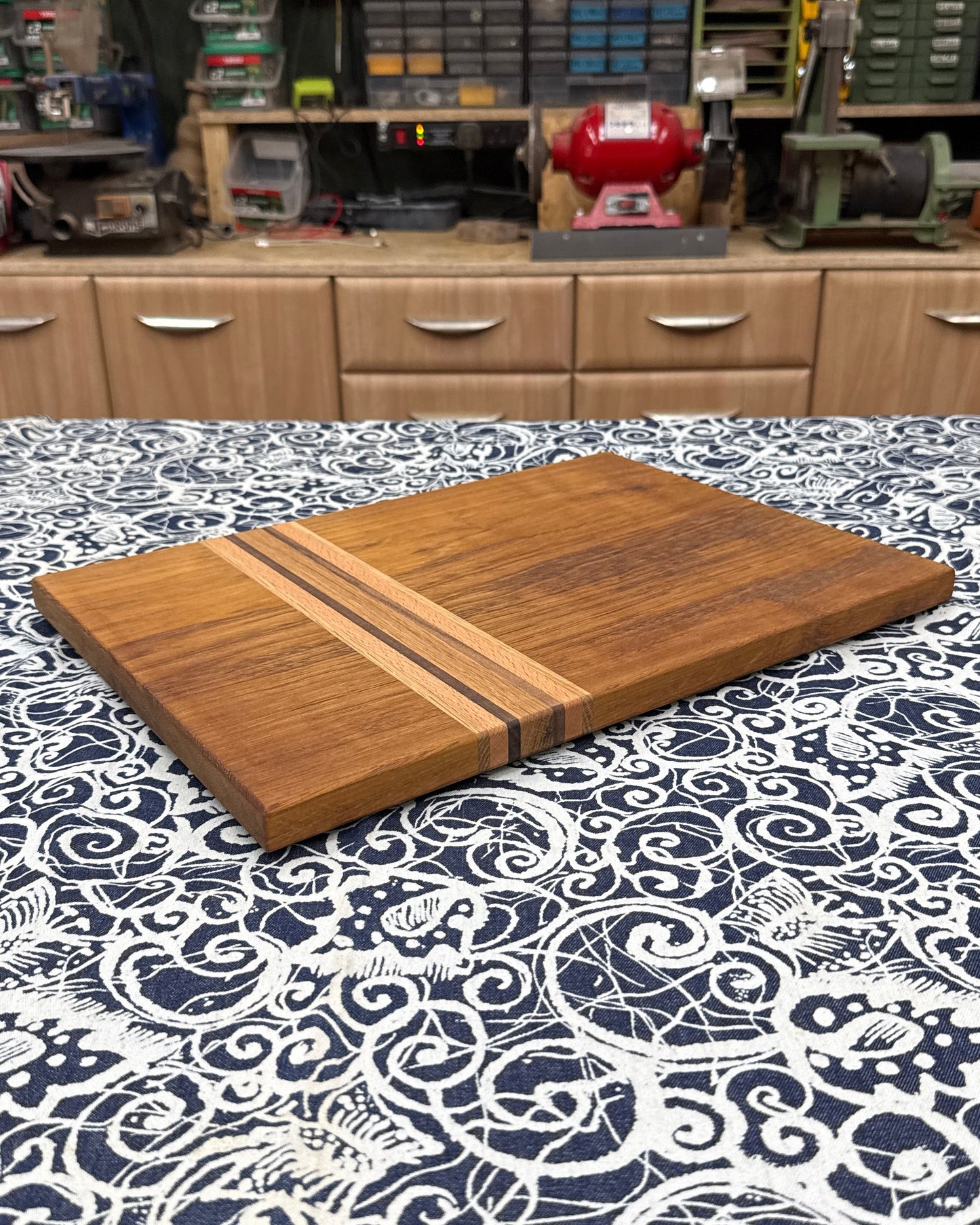 Wooden cutting board on a patterned tablecloth with a workshop in the background