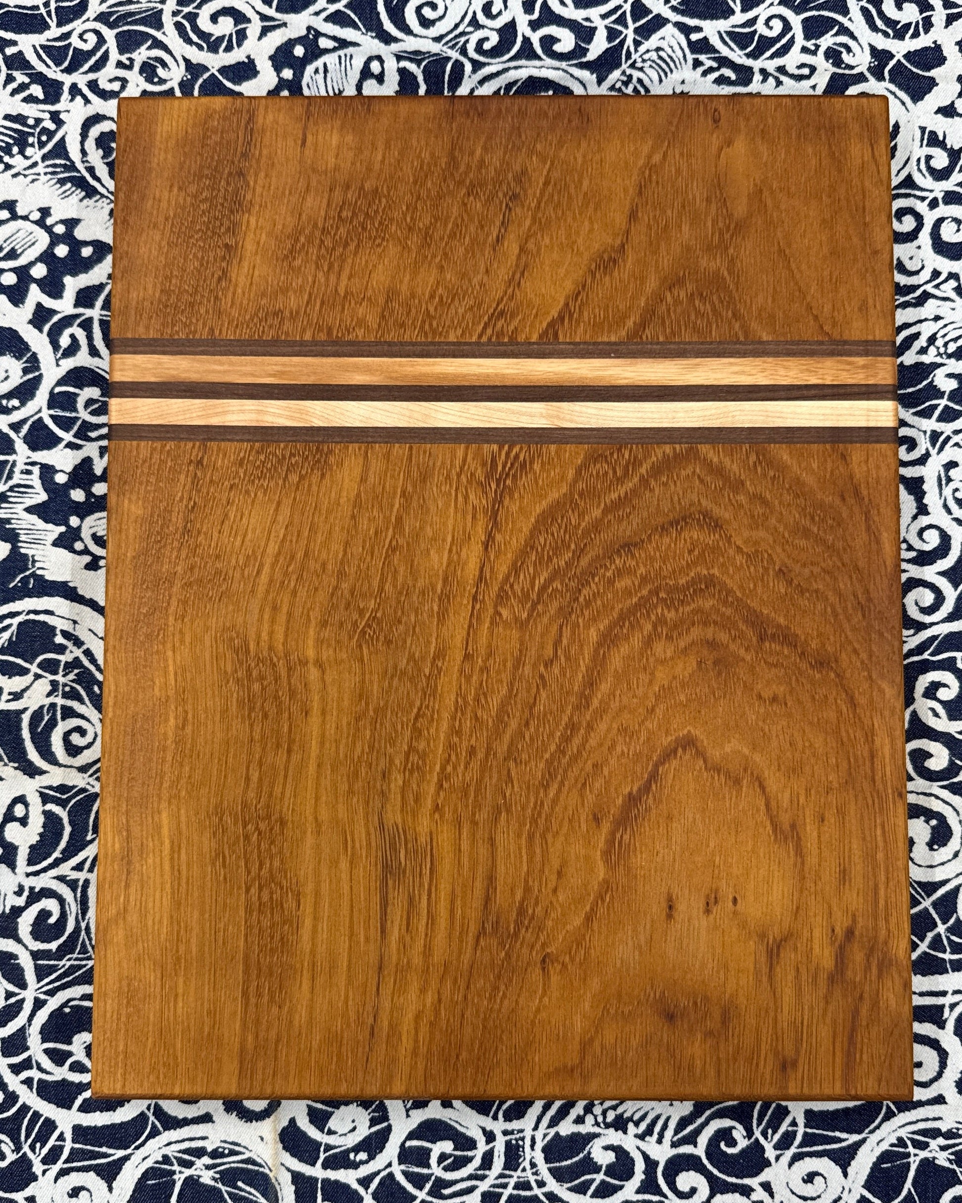 Wooden cutting board with metal strip on a patterned fabric background